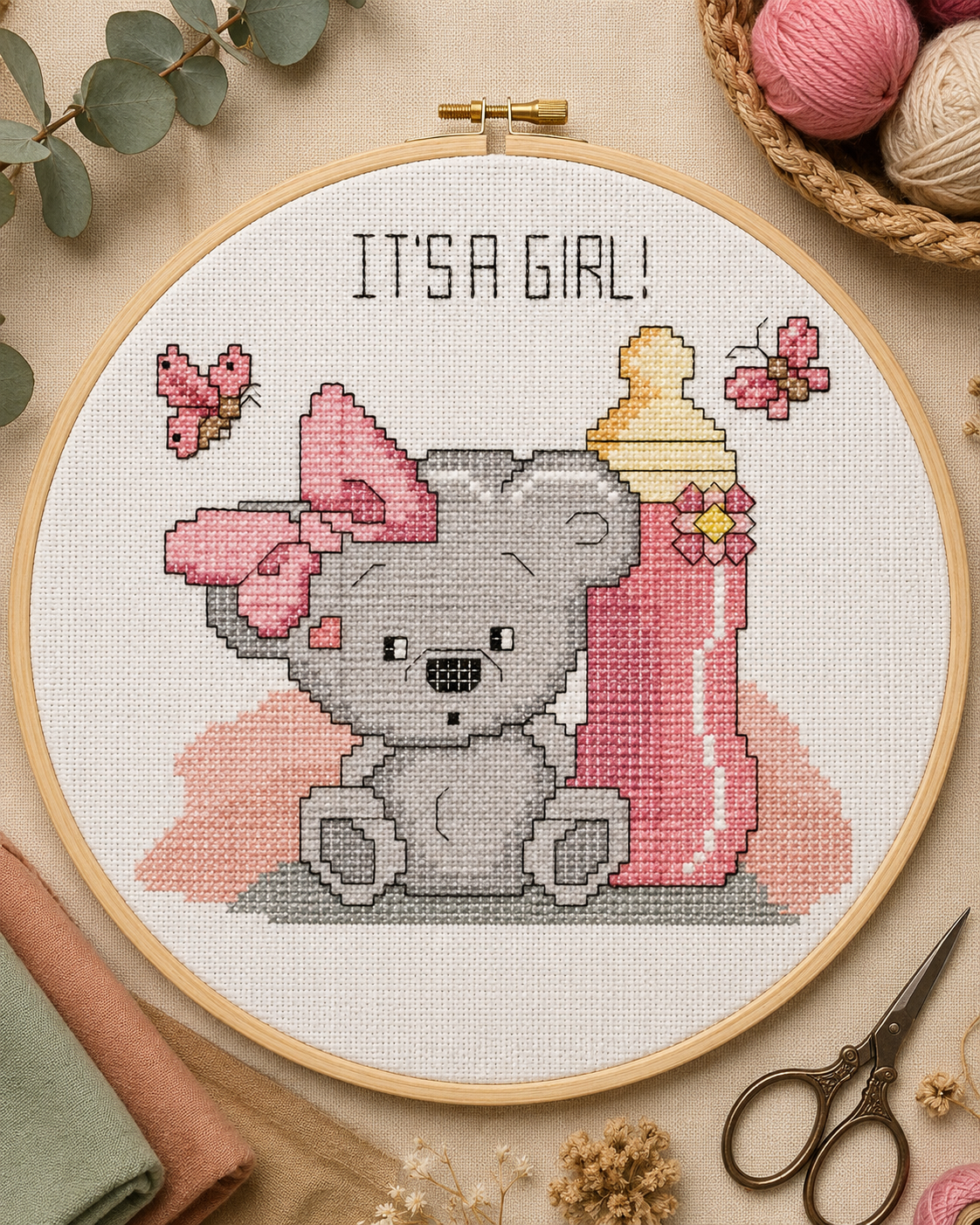 Bordado em ponto cruz para nascimento de menina com ursinho, biberão, laços, borboletas e frase It’s a Girl